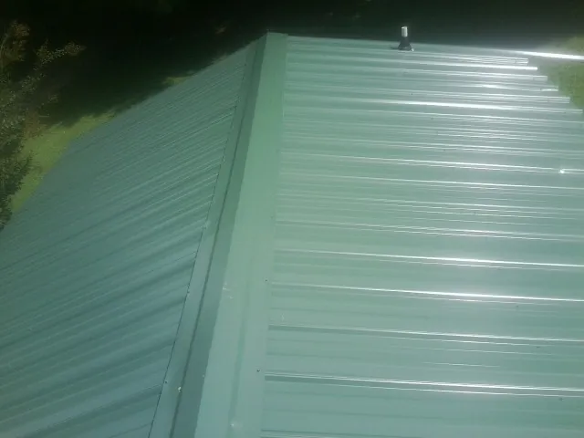 New green metal panels meeting at the ridge of a roof — Flat Roof Repair work by our crew in Tualatin