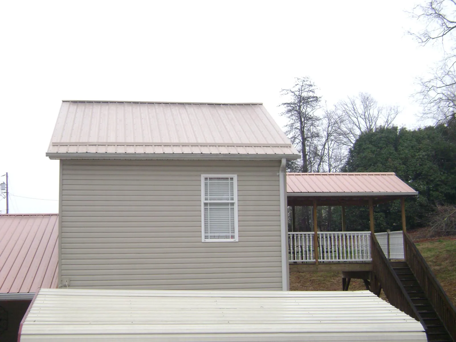 Tan metal roofs on a two story addition and attached porch, from a Roof Replacement job in Tualatin