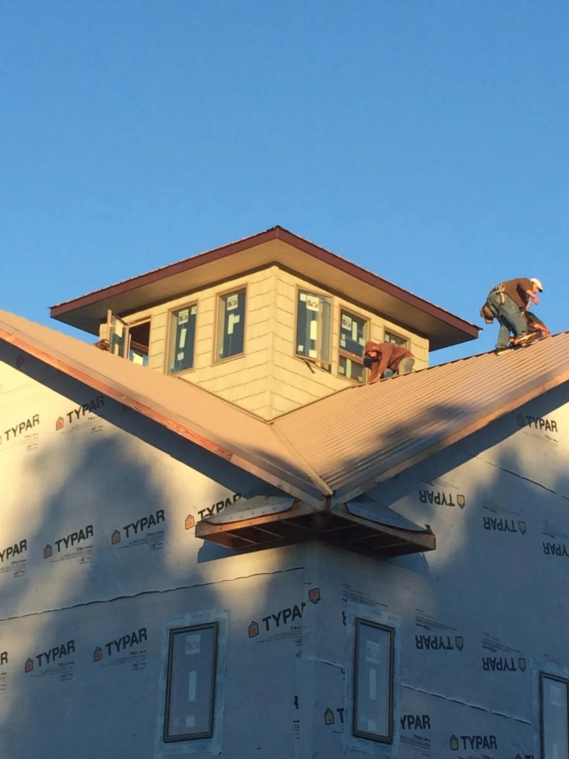 Roofers working around a rooftop cupola on a new metal roof at sunset — Roof Waterproofing in Tualatin by Roofing Brothers